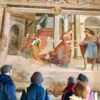 Group of people viewing an elaborate fresco within one of the chapels at Sacro Monte di Orta, Italy