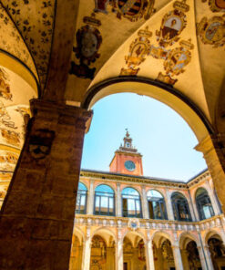 Courtyard of the Archiginnasio in Bologna, with frescoed vaults, coats of arms, and a view of the clock tower