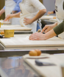 Hands-on pasta making class in Bologna, with students preparing dough on wooden boards