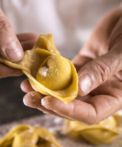 Artisanal tortellino pasta being carefully folded by hand, showcasing a traditional Bolognese skill