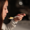 Woman savoring a spoonful of freshly made tortellini after a Bologna cooking class, with wine in the foreground